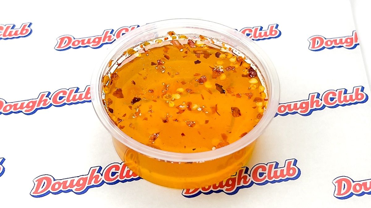 A pot of Dough Club hot honey, flecked with chilli
